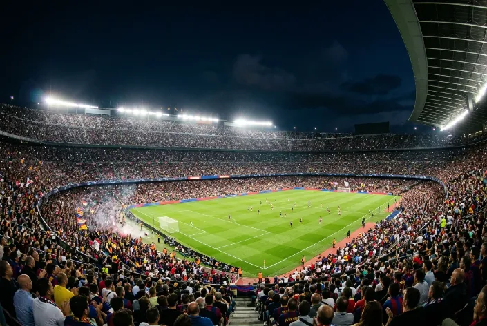 Estadio lotado durante um jogo nocturno da Champions League com iluminacao intensa